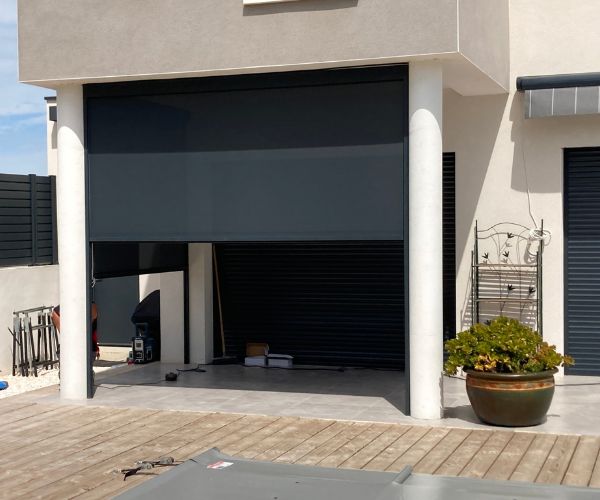 Store vertical en cours de pose pour protéger une terrasse du vent à Vendres